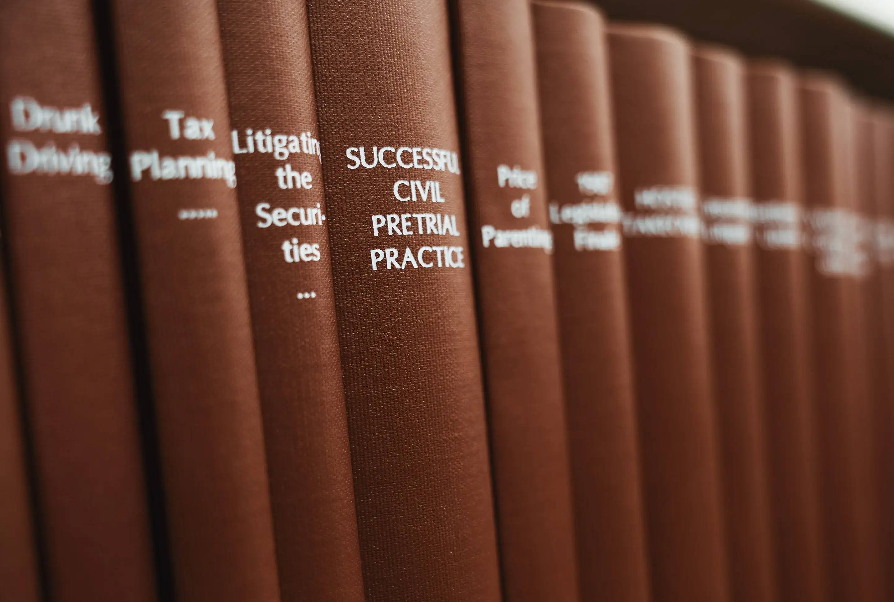 A row of red-brown law books on a library shelf, the spine reading Successful Civil Pretrial Practice in focus
