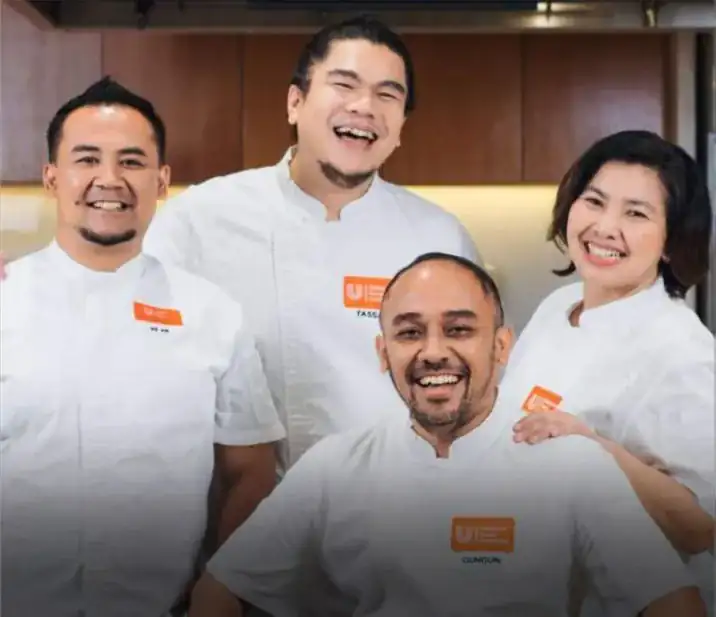 Four Unilever Food Solutions chefs in white jackets laughing in a kitchen, Chef Gun Gun seated at the front