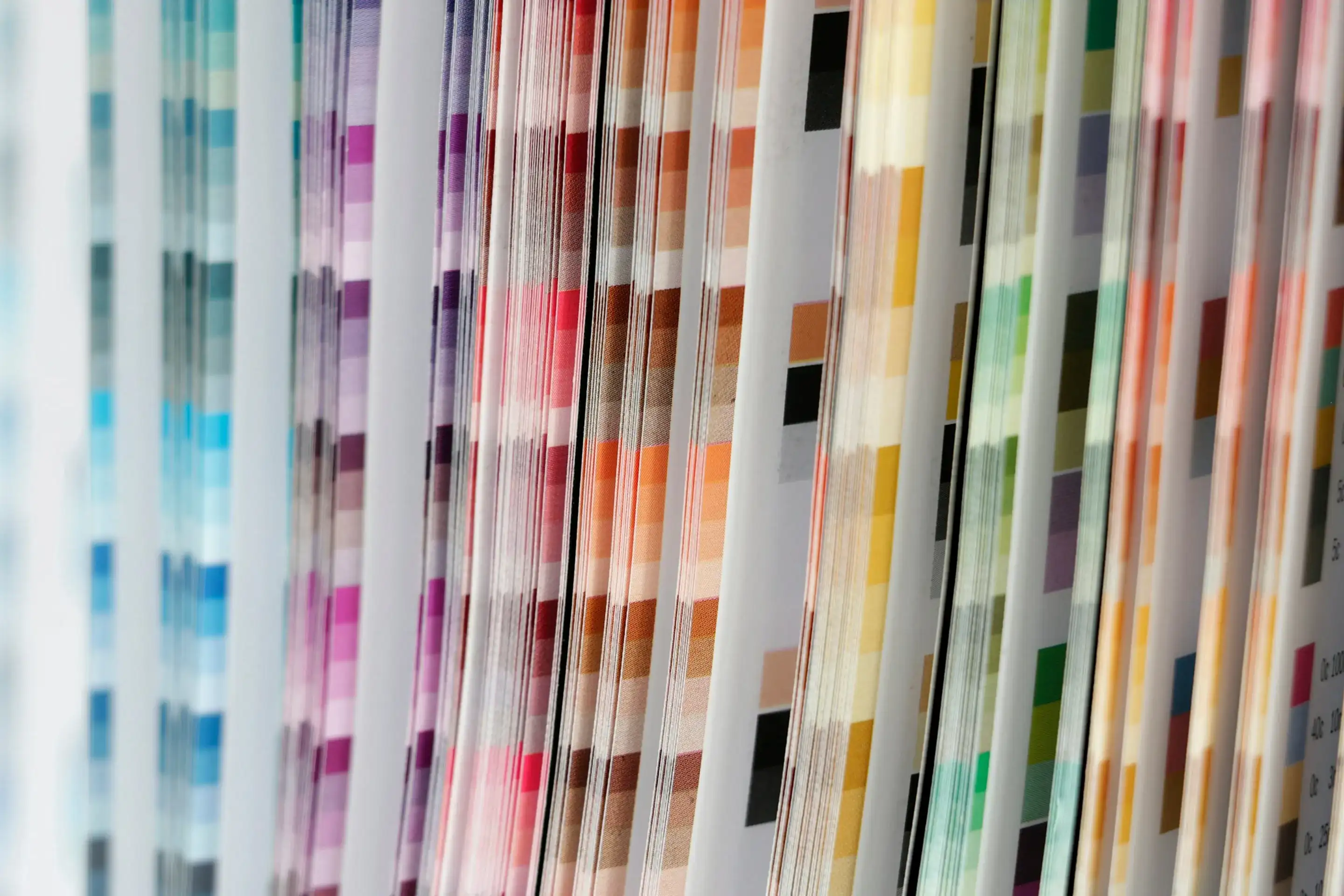 The pages of a colour fan deck, rows of paint swatches from blue to red