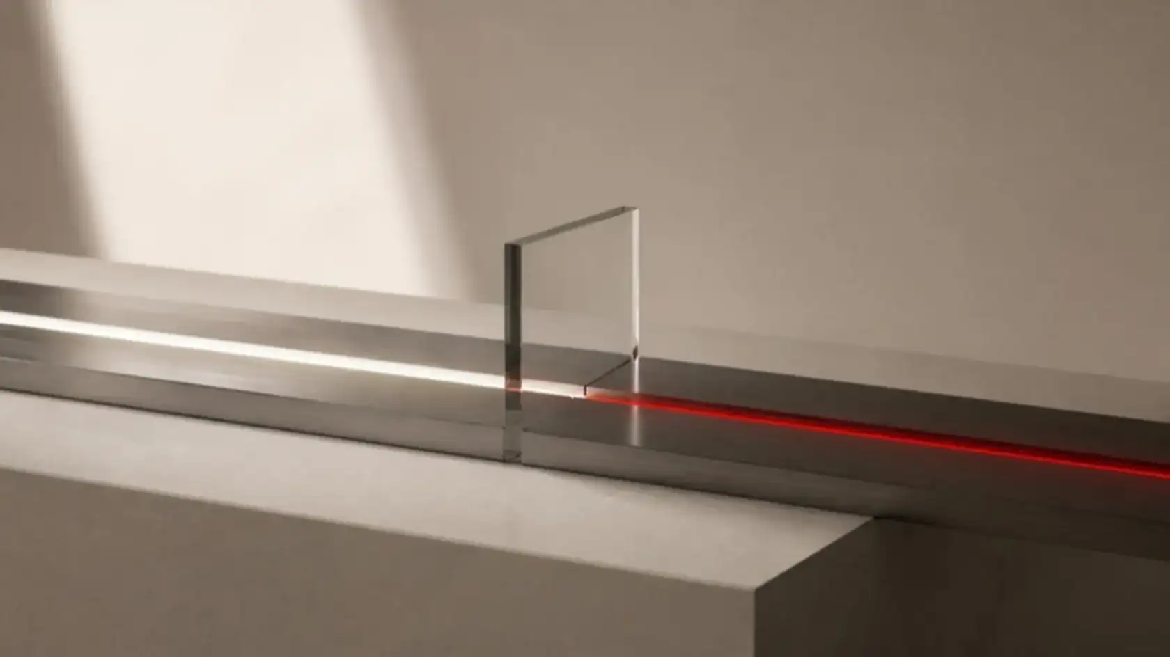 A clear glass pane standing in a steel channel, the white light running along the channel turning red where it passes through