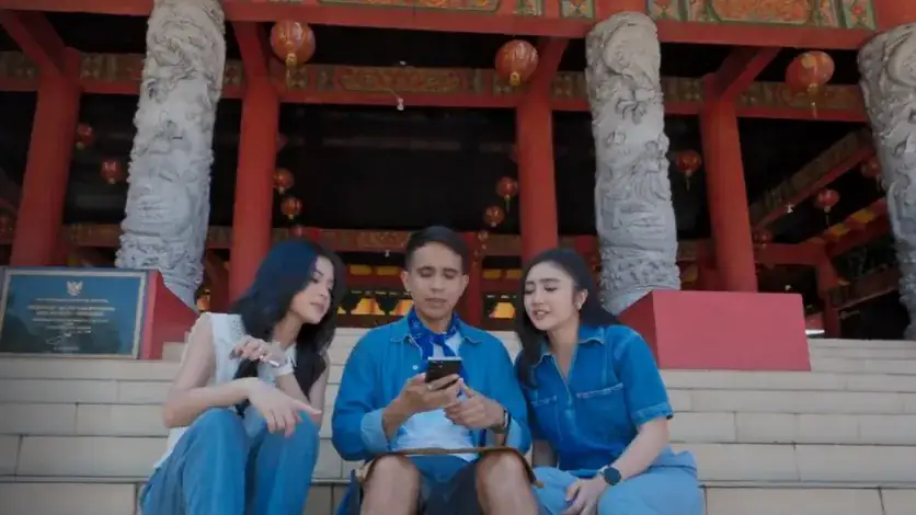 Three hosts on temple steps looking at a Galaxy phone, a still from the Galaxy Quest of Indonesia series